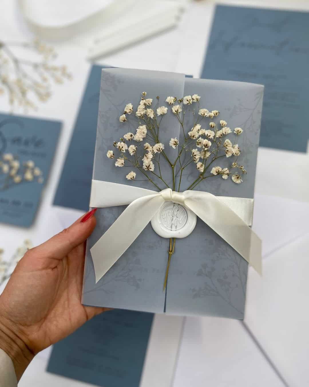 Blauwe trouwkaartjes met gipskruid voor iets ouds, geleends, blauws 